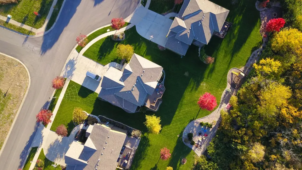 Aerial view of large homes on generous lots framed by red and gold autumn trees