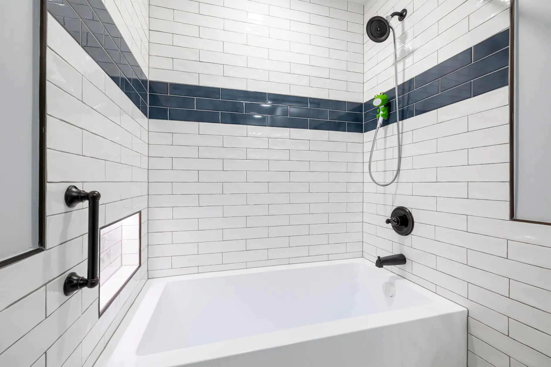 Refinished white bathtub in a subway-tiled alcove with a navy accent band