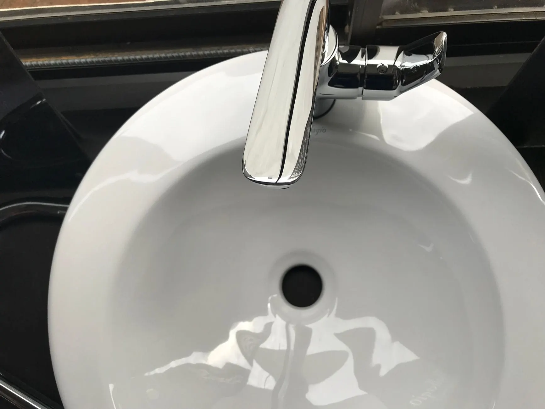 Close-up of a round white sink basin reglazed to a clean gloss under a chrome faucet