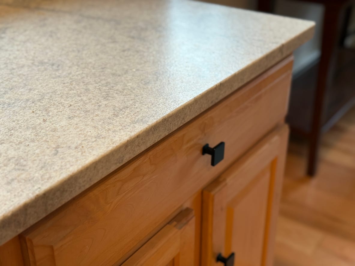 Close-up of a countertop refinished in a speckled stone-look finish above maple cabinets