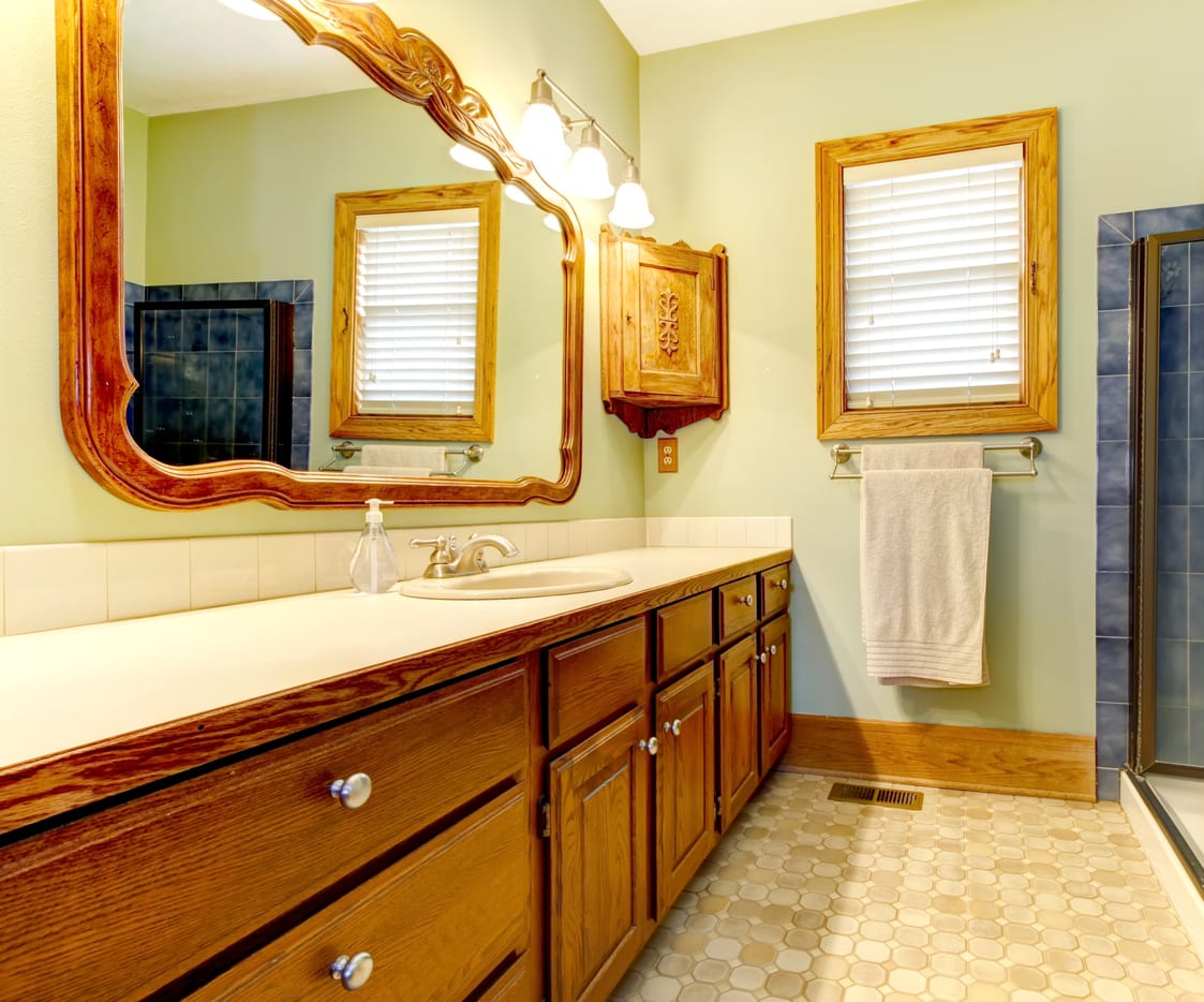 Bathroom vanity with a refinished cream countertop and integrated sink beneath a framed mirror